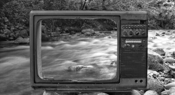 retro tv on river shore near forest